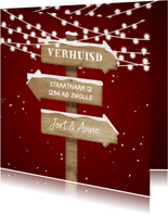 Kerst-verhuiskaart met lampjes, sneeuw en wegwijzerbord