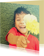 Wenskaart met een lachend kind die twee bloemen vasthoudt