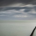 Rouwkaart met golfbreker wolken en ondergaande zon Achterkant