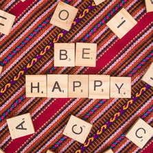 Wenskaart met houten letters ‘be happy’ op Peruaanse stof