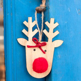 Kerstkaart met een houten rendier op een blauwe deur