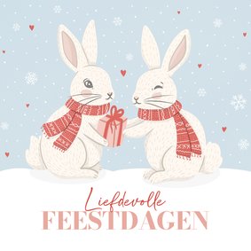 Kerstkaart met konijnen in de sneeuw liefdevolle feestdagen