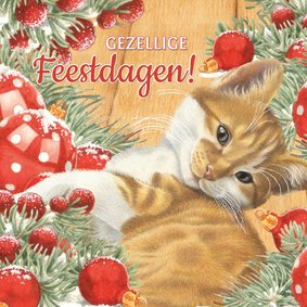 Kerstkaart met rode kitten bij de kerstversiering