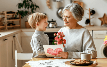 kleinzoon geeft oma bloemen en een tekening