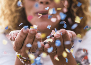 Vrouw blaas confetti richting camera