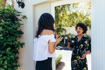 vrouw geeft housewarming cadeau aan andere vrouw