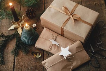 Kerstcadeaus bij kaars en dennentakken