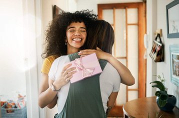 vrouw omarmt andere vrouw met cadeau in hand