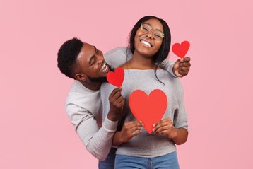 Man en vrouw houden rode hartjes in hun handen vast