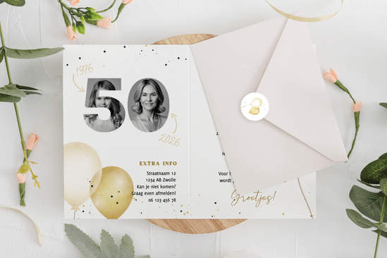 opengeslagen uitnodiging met envelop en bloemen