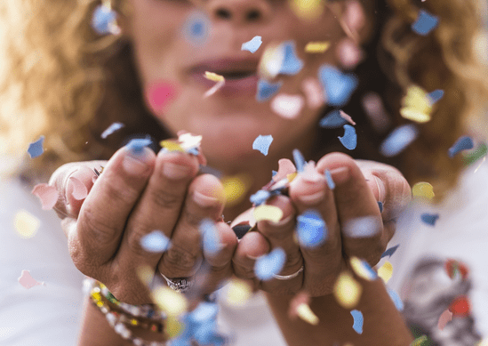 Vrouw blaas confetti richting camera