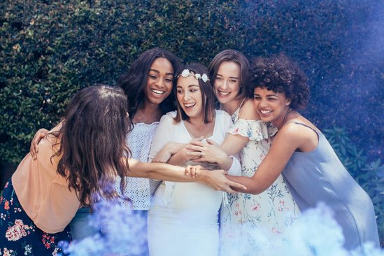 Vriendinnen omhelzen zwangere vrouw bij gender reveal party