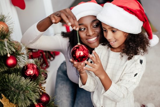 Moeder en kind hangen kerstbal in kerstboom