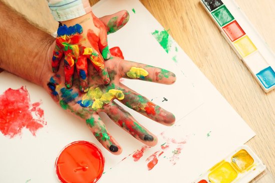 Kinderhand in vaderhand met vingerverf
