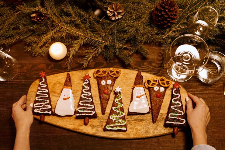 Kerstkoekjes in de vorm van kerstboom, rendier en sneeuwpop op serveerplank