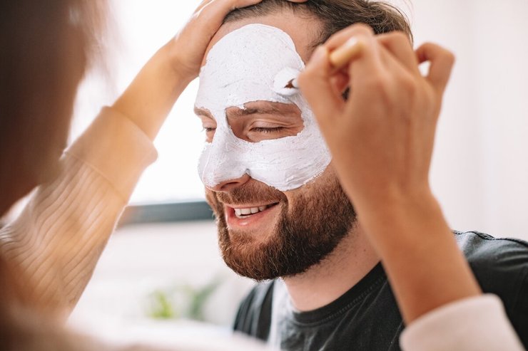 Vrouw geeft haar man een wellness gezichtsmasker