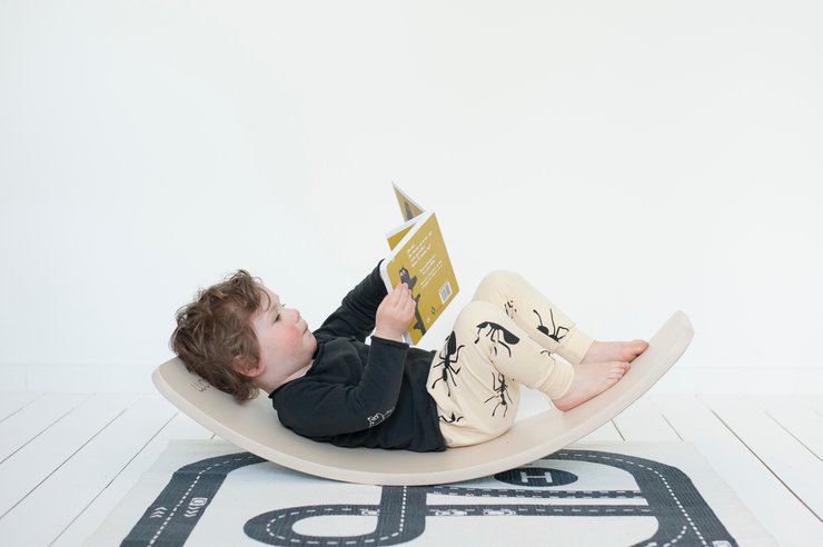 Kindje leest boek op houten wobbel