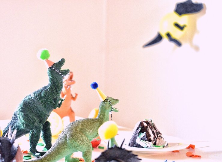 Taart omringt door dino's met feestmutsjes op