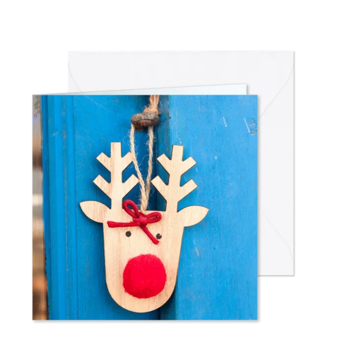 Kerstkaart met een houten rendier op een blauwe deur