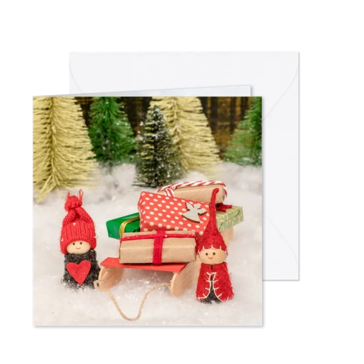 Kerstkaart met twee elfjes en een slee vol cadeautjes