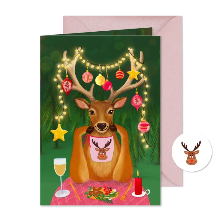 Vrolijke kerstkaart met rendier aan tafel