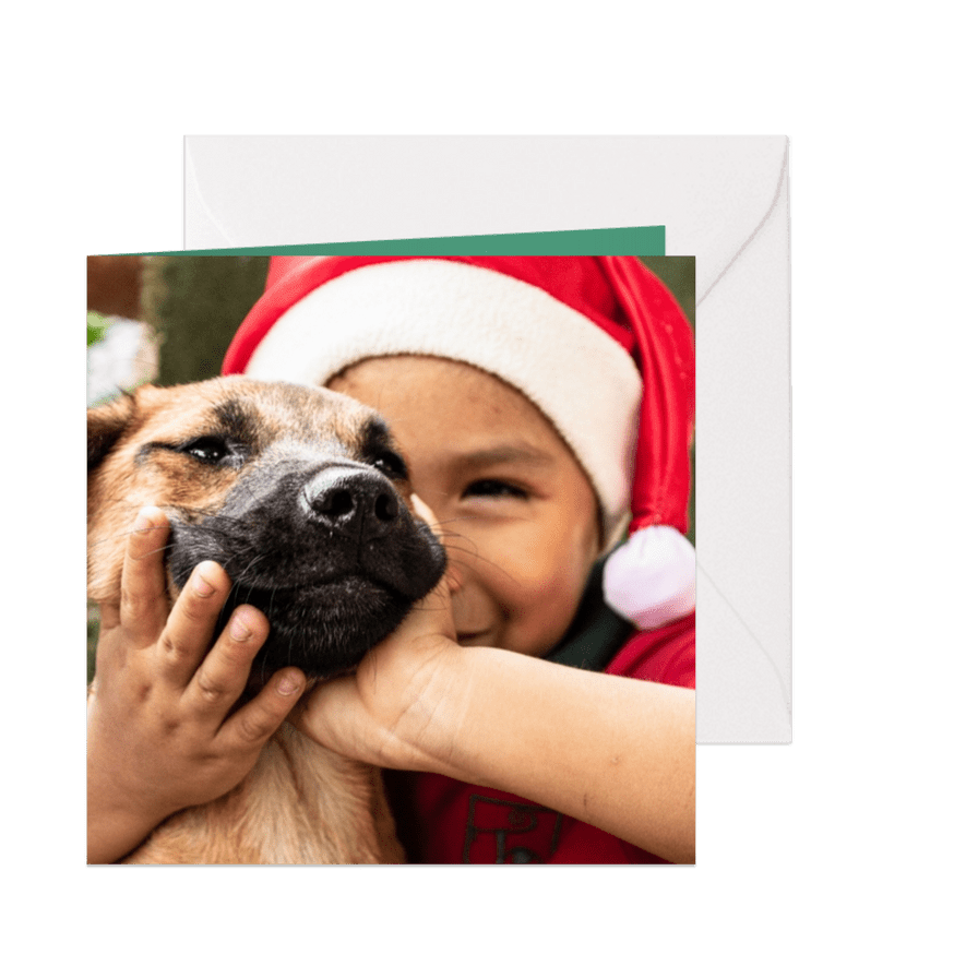 Kerstkaart met een kind met een kerstmuts en een hondje aait - Kaartimpressie